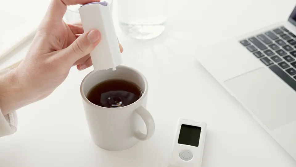 Mano añadiendo edulcorante a un café