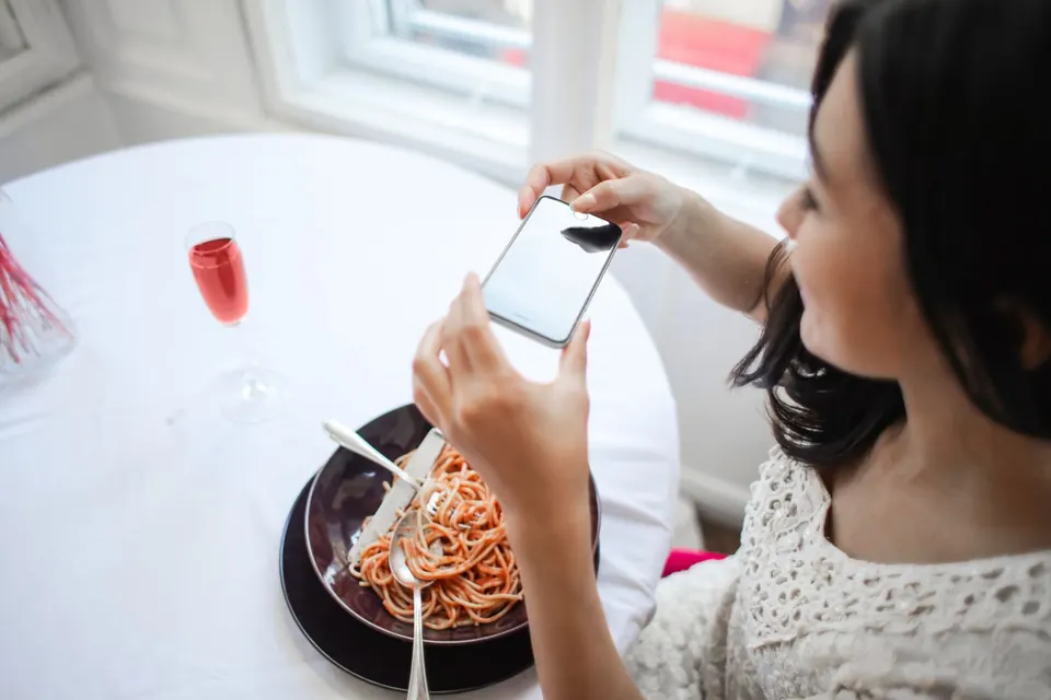 Mujer fotografiando su comida con el celular